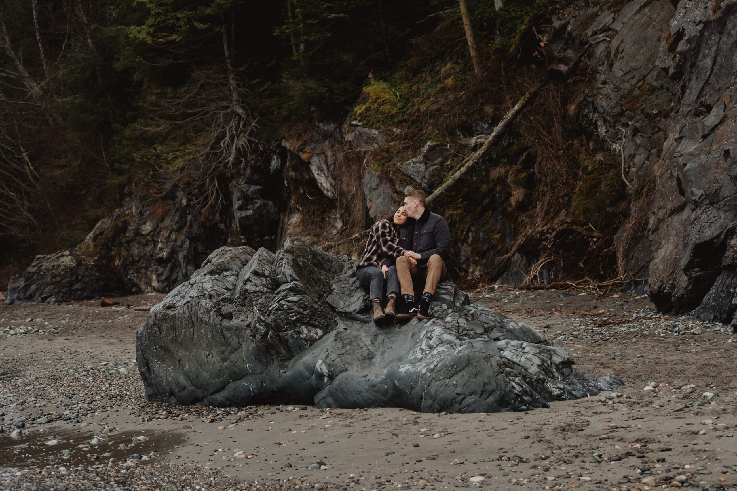a couple posing together on a rock for their engagement session at Deception Pass State Park