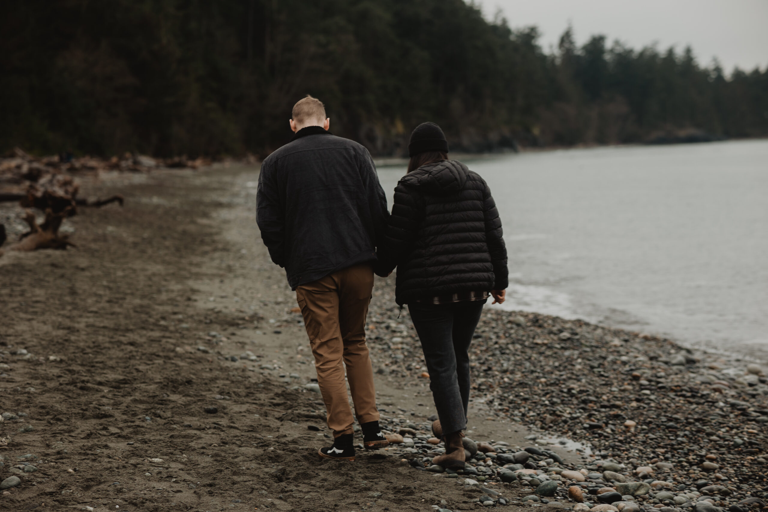 a couple posing together on the beach for their engagement session at Deception Pass State Park